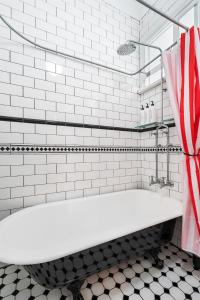 Una bañera blanca en un baño con azulejos blancos. en Miller's On Kent - In The Heart Of Sydney!, en Sídney 38 fotos más