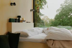 an unmade bed in a room with a window at Raus Tiny House am See mit Sauna und Whirlpool in Lenzen