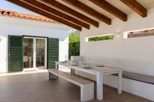 a wooden table with a bench on a patio at Villa Maravilla with HEATABLE pool ROOFTOPbar with sea views in Binibeca