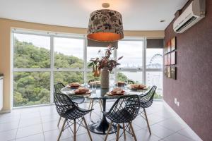 a dining room with a table with chairs and a large window at Lindo Apto no Terraços da Rainha in Balneário Camboriú