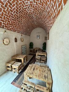 a room with wooden tables and a brick wall at Dar alibaba in Douz