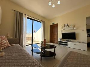 a living room with a couch and a tv and a table at Radiant 2BED penthouse Mellieha!! by Homely in Ix-Xagħra taʼ Barra