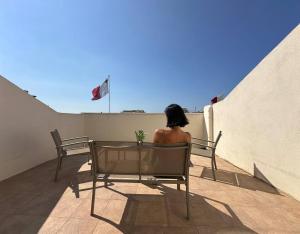 a woman sitting in a chair on a balcony at Radiant 2BED penthouse Mellieha!! by Homely in Ix-Xagħra taʼ Barra