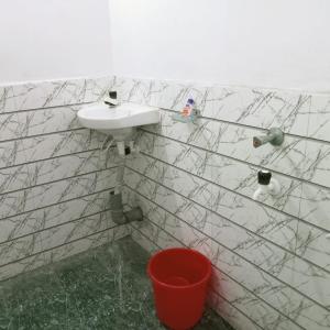 a bathroom with a sink and a red bucket at Panchalaya Homestay in Guwahati +51 photos
