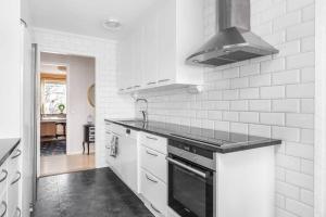 a kitchen with white cabinets and a stove top oven at Villa Veranda in Linköping