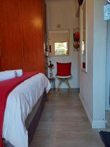 a bedroom with a bed and a red chair at La Grâce, Durbanville in Cape Town
