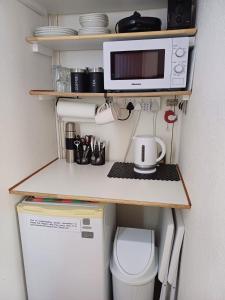 a small kitchen with a microwave and a refrigerator at La Grâce, Durbanville in Cape Town