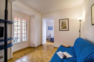 Una sala de estar con un sofá azul y una ventana. en Résidence Partenaire Le Palais de la Marine, en Villefranche-sur-Mer