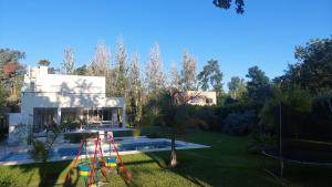 ein Haus mit einem Spielplatz vor einem Hof in der Unterkunft Casa Ravi in Pilar