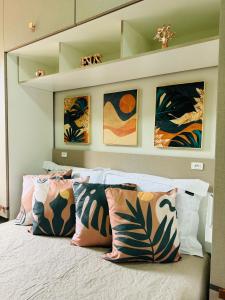 a bedroom with a bed with pillows and paintings at Stúdio equipado em Xerém - St 7 in Xerém