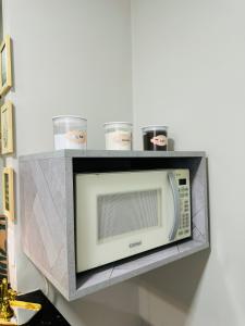 a microwave on a shelf in a room at Stúdio equipado em Xerém - St 7 in Xerém