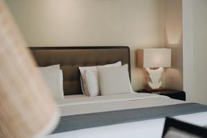 a bedroom with a bed with white pillows and a lamp at Kula Kara Villas Bingin, Uluwatu in Uluwatu