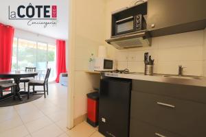a kitchen with a sink and a microwave and a table at le mas in La Pastissière