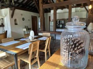 a dining room with a table and a glass jar with pine cones at La bergerie de lesbordes in Lestajaou