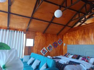 a living room with a blue couch and two beds at Uros Lake Titicaca Lodge in Puno