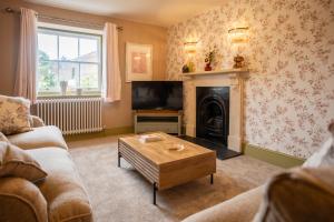 ein Wohnzimmer mit Kamin und Fernseher in der Unterkunft The Maze Garden Cottage by Mint Stays in Biddlestone