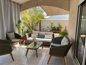 a living room with a couch and chairs on a patio at Villa Étang salé les bains avec piscine privée in Étang-Salé les Bains