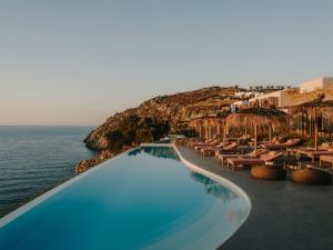 a swimming pool with chairs and the ocean at The Wild by Interni in Kalafatis