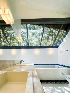 a bathroom with a sink and a tub and windows at Arquitetura única na Granja Viana in Jandira
