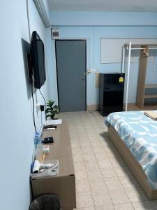 a bedroom with a bed and a desk with a tv at KPP Mansion in Amphoe Phra Khanong