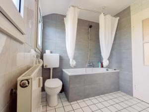 a bathroom with a toilet and a tub and a sink at City House Neuss in Neuss