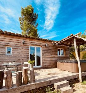 een houten hut met een terras en een tafel bij La cabane du Mas gnolia in Saint-Jean-du-Gard