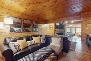 a living room with a leather couch and wooden walls at Lakeview Hideaway in Ellijay