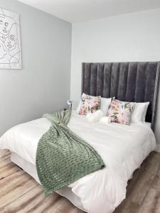 a white bed with a gray headboard and pillows at Osheni City Center Apartment in Windhoek