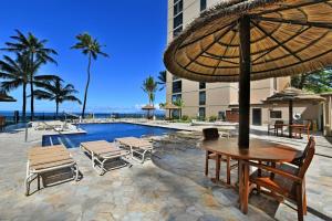 a pool with a table and chairs and an umbrella at Ocean Front Gorgeous Views in Kahana