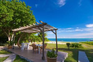 un patio con tavolo, sedie e spiaggia di Amitie Chalets Praslin a Grand Anse