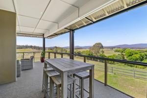 a patio with a wooden table and chairs on a balcony at Mountain Majesty with Poolside Relaxing Getaway in Tamborine +8 photos