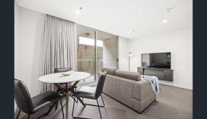 Una sala de estar con un sofá, una mesa y sillas. en Happy BNB deluxe suit in adelaide CBD, en Adelaida
