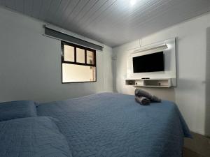 una camera da letto con un letto e una TV a schermo piatto di BS01- Casa com Piscina Aquecida e Churrasqueira a Balneário Barra do Sul