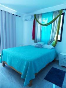 a bedroom with a blue bed with a window at Residencial Victoria in Sampiño