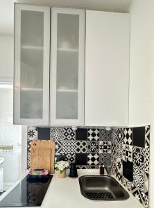 a kitchen with white cabinets and black and white tiles at WOW Urban Nest Saarbrücken in Scheidt