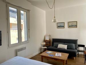a living room with a couch and a table at Grand Studio centre ville, gare et plage à pied in Pornichet