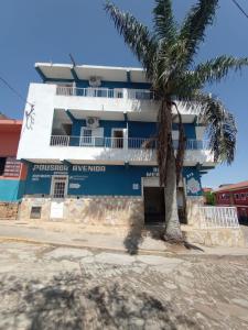 a building with a palm tree in front of it at Apartamento avenida 06 com ar condicionado in São Thomé das Letras