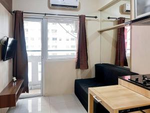 雅加达2BR Apt Green Pramuka with Pool & Wi-Fi by 2ndHome的带沙发和大窗户的客厅