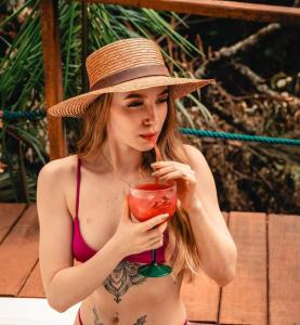 a woman in a hat is holding a drink at Chalés Senhor Dos Trilhos in Mairiporã