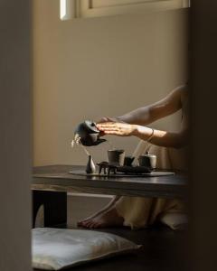 Una mujer está sentada en una mesa con tazas. en Yeojuhyeon Dongcheon, en Chilgok