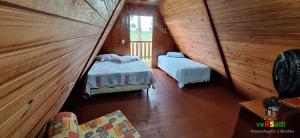 オソリオにあるChalé Caiu do Céu ll Wi-Fi Nômade Digital ll Táxi Fácil II Quiosque Churrasqueira ll Forno Microondas ll 6km da Estrada do Mar ll 7km Parque de Rodeio ll 8,1Km Prefeitura II 7,2Km UFRGS Litoral II 12km do Morro Borrúsia e Praias de Tramandaíの木造キャビン内のベッド2台が備わる部屋