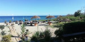 ein Strand mit Stühlen und Sonnenschirmen und das Meer in der Unterkunft Les pieds dans l'eau in San-Nicolao
