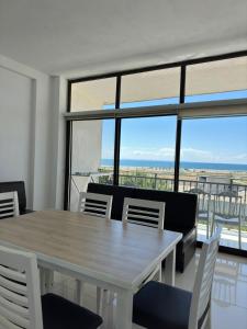 a dining room with a table and chairs and windows at Flat Ergli in Velipojë