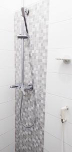 a shower in a bathroom with a tiled wall at Sarwi Endah Beach Cottage in Tepus