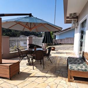 un patio con ombrellone, tavolo e sedie di Suíte próximo a Vila Germânica a Blumenau