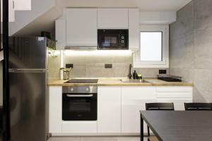 Una cocina con gabinetes blancos y un refrigerador de acero inoxidable. en Mediterranean Bliss, en Sant Adrià de Besòs