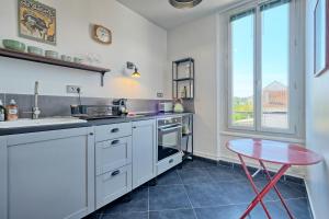 a kitchen with white cabinets and a table and a window at T2 Art Déco proche Disney-Paris-Parking in Esbly +10 photos