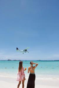 two women standing on the beach with an airplane in the sky at Pearl Beach Hotel in Saint-Jean +38 photos