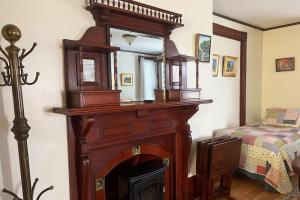 Un espejo encima de una chimenea en un dormitorio. en Falls Farmstead 1865 Ellis House Cozy and Comfy Apt #1, en Ellsworth