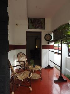 a living room with chairs and a table and a clock at Shoreline Marari Beach Villa At Golden Beach Mararikulam in Alleppey